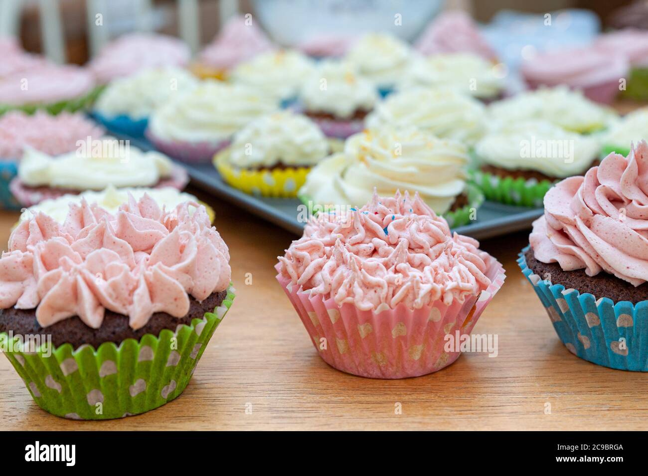 Cupcakes cotto in casa splendidamente decorato con crema di burro sulla parte superiore posto su tavolo di legno. Foto Stock