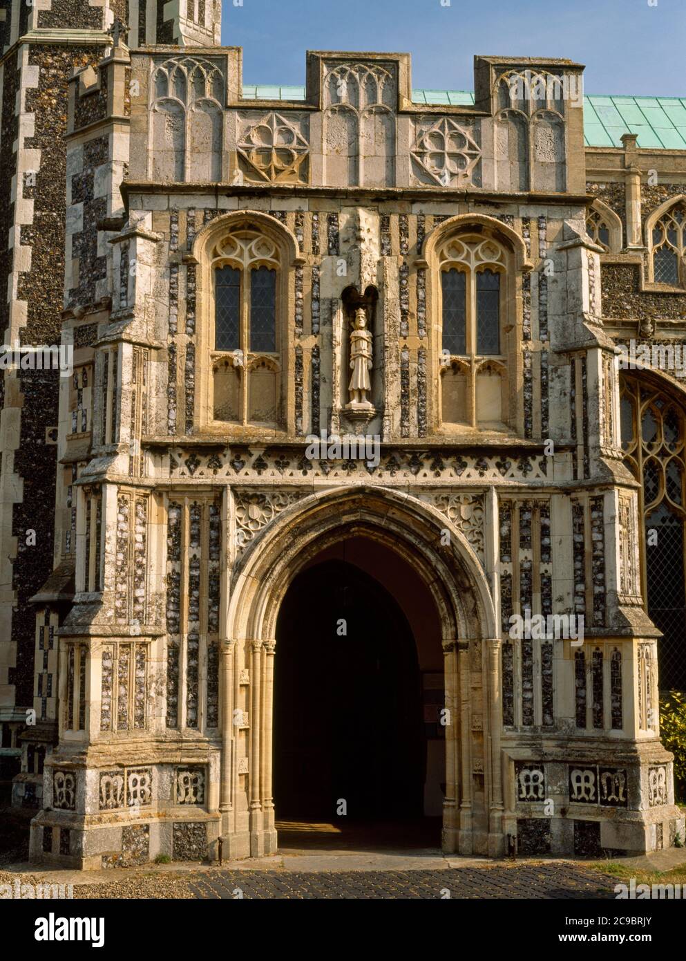 Il portico perpendicolare a S del C15 della chiesa di St Edmund, Southwold, Suffolk, Inghilterra, Regno Unito, con una statua moderna di Re Edmund in una nicchia canoped. Foto Stock