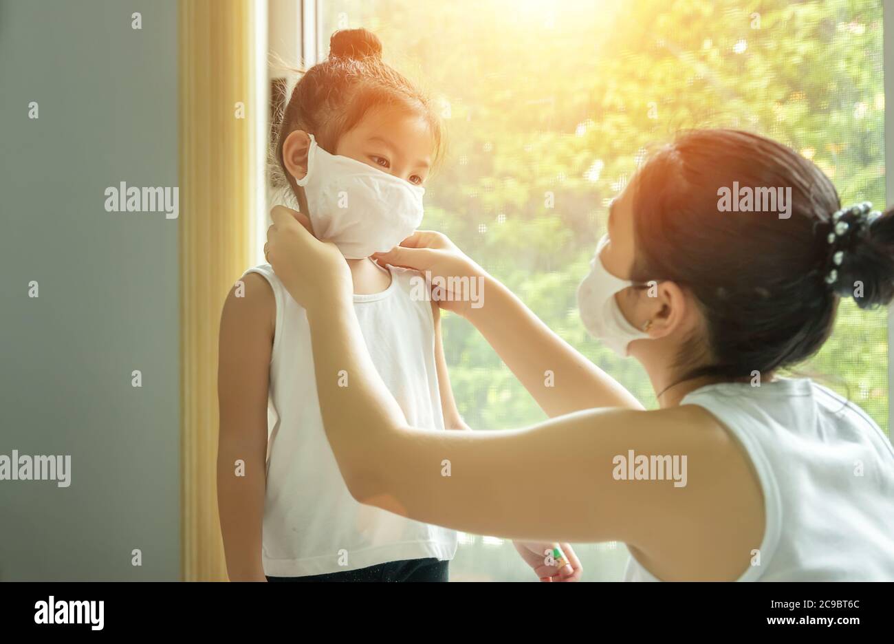 Famiglia asiatica con bambini in maschera di faccia, madre si prepara a mettere la maschera di faccia sul suo bambino prima di lasciare casa per andare a scuola, nuovo concetto normale Foto Stock