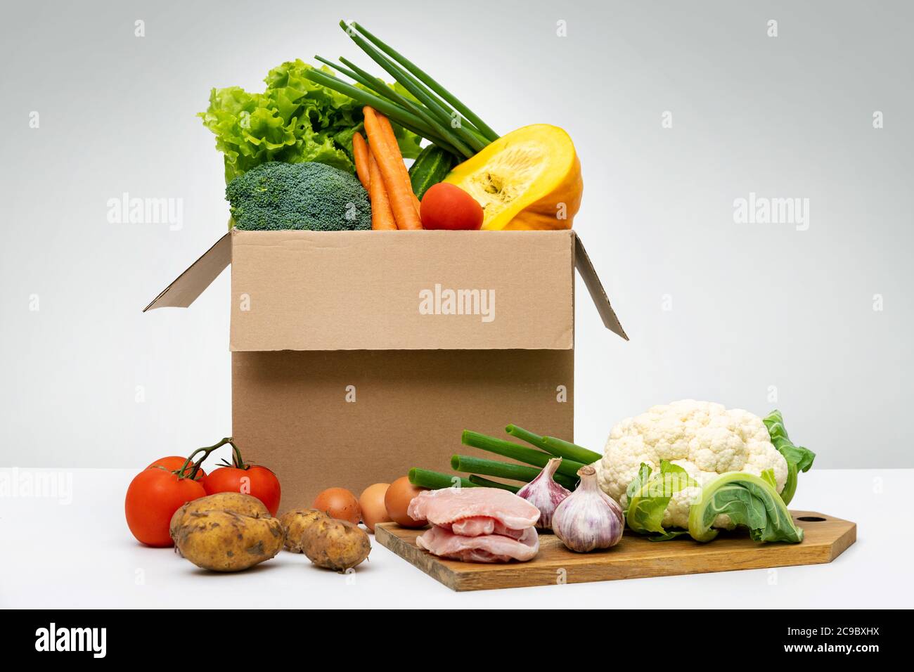 cibo agricolo fresco biologico - gruppo di verdure uova e carne in scatola di cartone Foto Stock