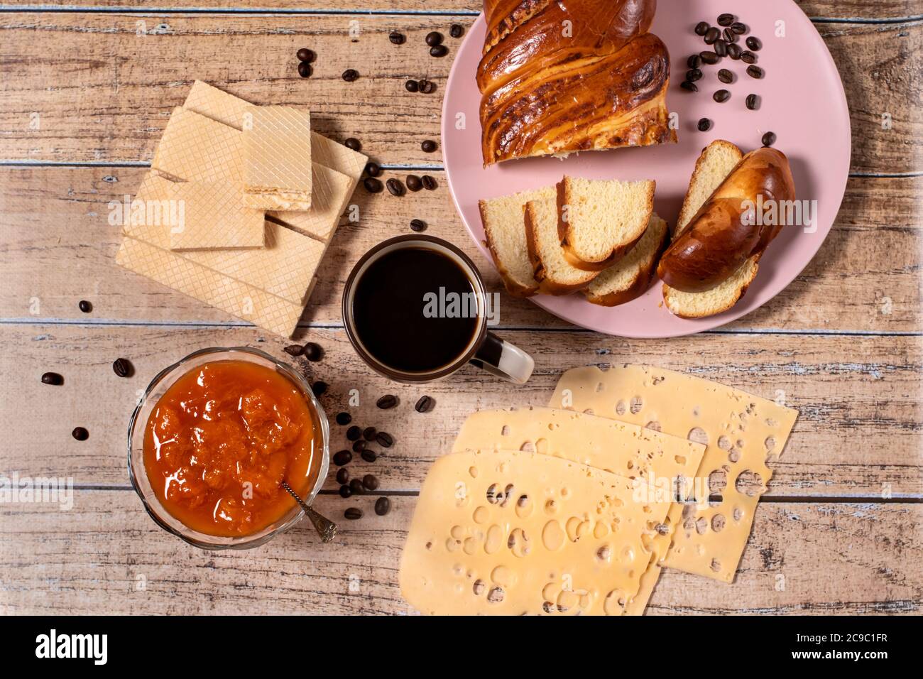 L'idea di una deliziosa colazione per tutta la famiglia. Panino di vimini, formaggio, marmellata di albicocche, waffle e caffè nero aromatico. Layout. Foto Stock