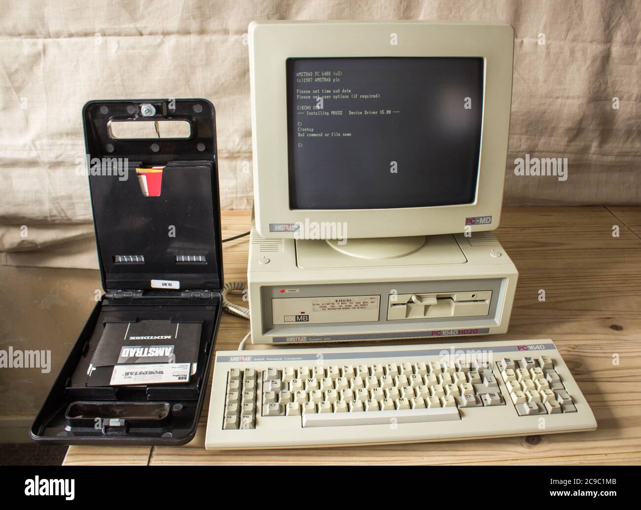 Vintage Amstrad PC1640HD20, computer storico su scrivania con scatola di dischi floppy da 3.5 pollici. Foto Stock