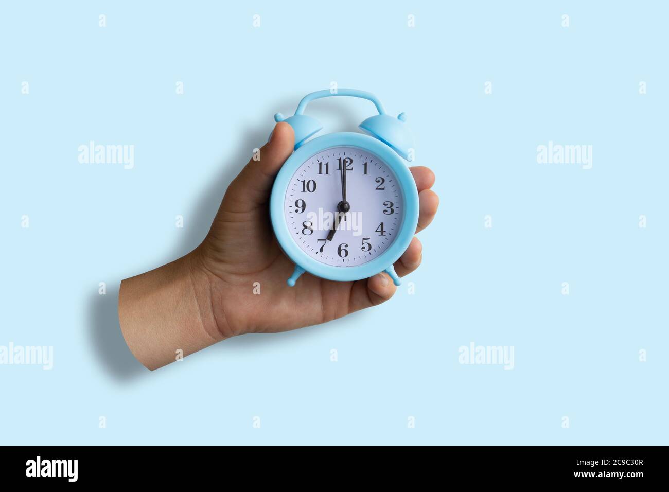 Orologio sveglia blu con mano femmina su sfondo azzurro Foto stock - Alamy