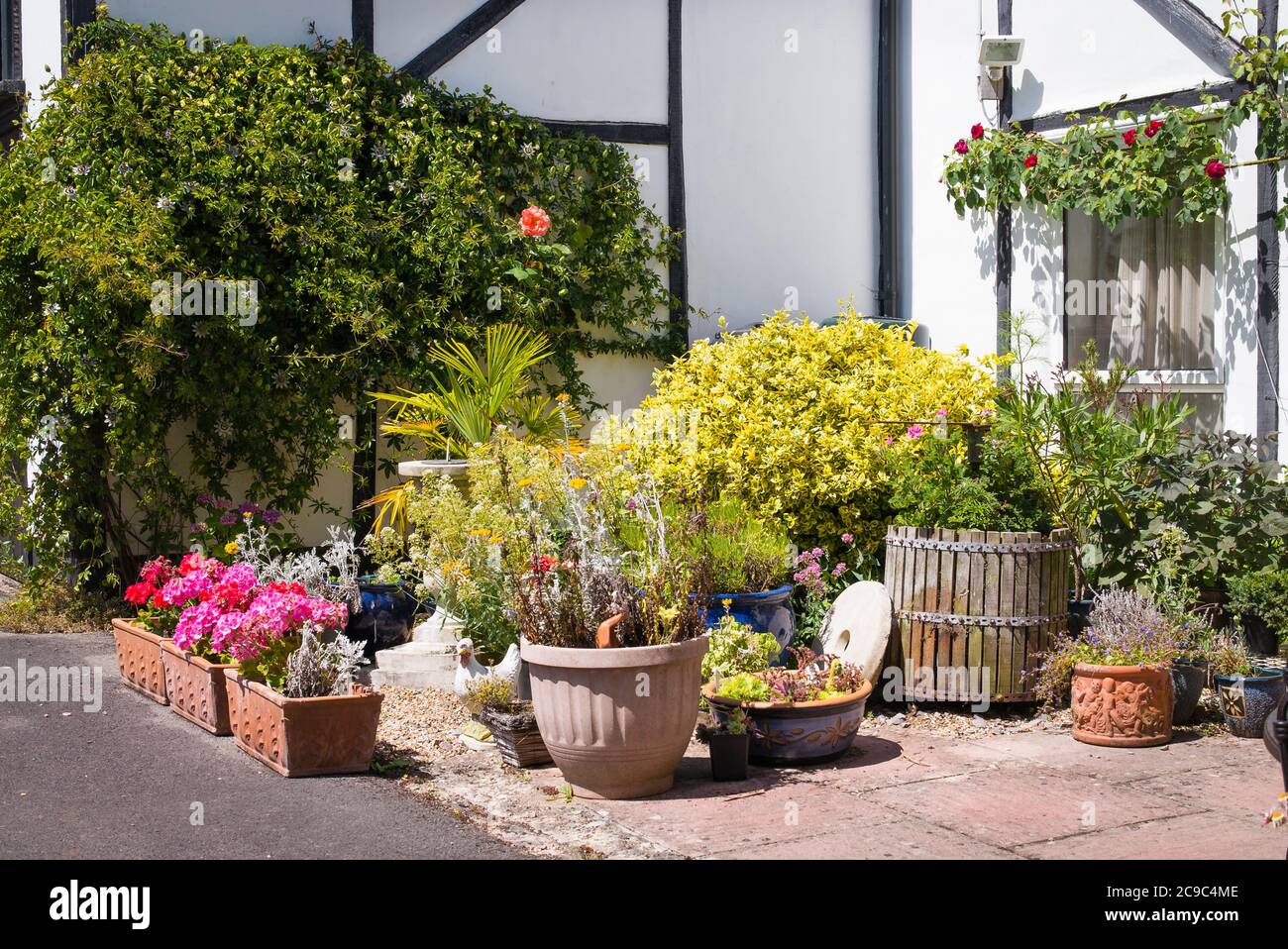 Un piccolo patio giardino accanto a un vecchio fienile convertito in un giardino inglese nel mese di luglio Foto Stock
