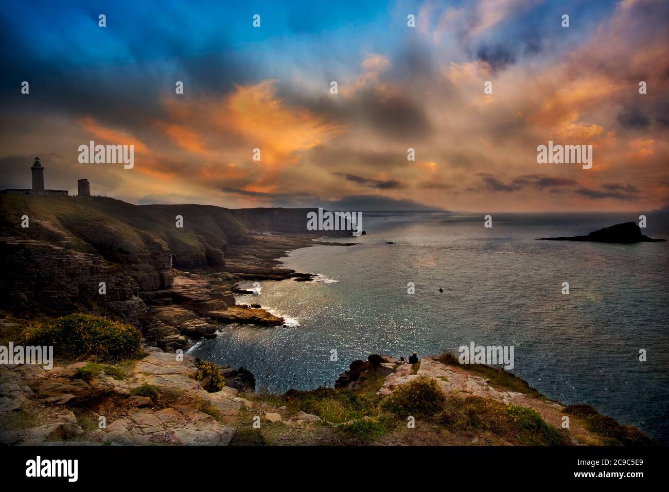 Côte de Granite Rose, Bretagna, Francia. Spettacolare tramonto sulla scogliera che si affaccia sull'oceano e sui fari di Cap Fréhel. Nuvole rosse nel cielo. Foto Stock