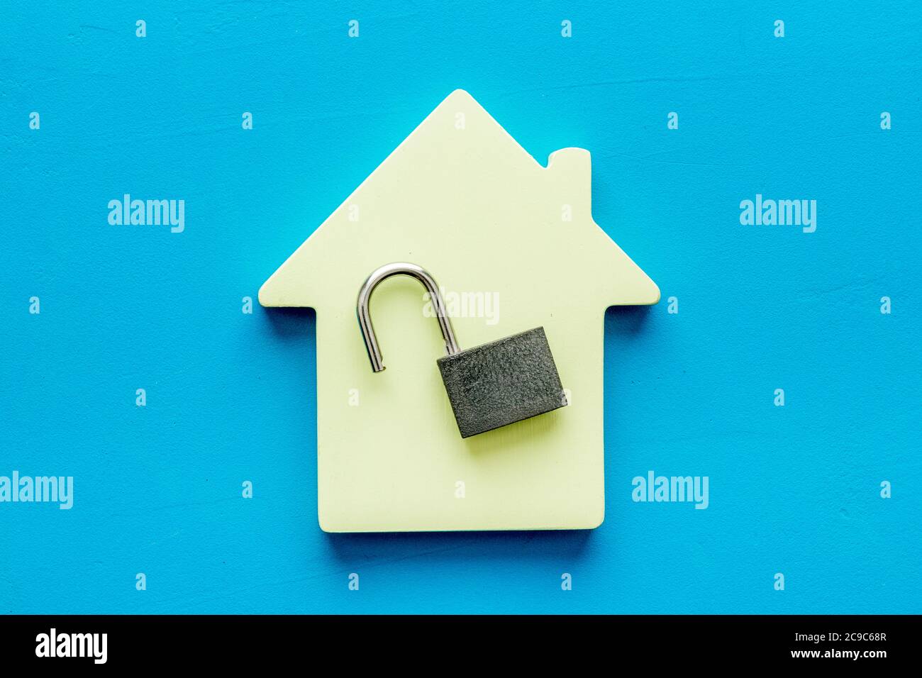 Concetto di sicurezza - serratura e figura della casa - sulla scrivania blu dall'alto verso il basso Foto Stock