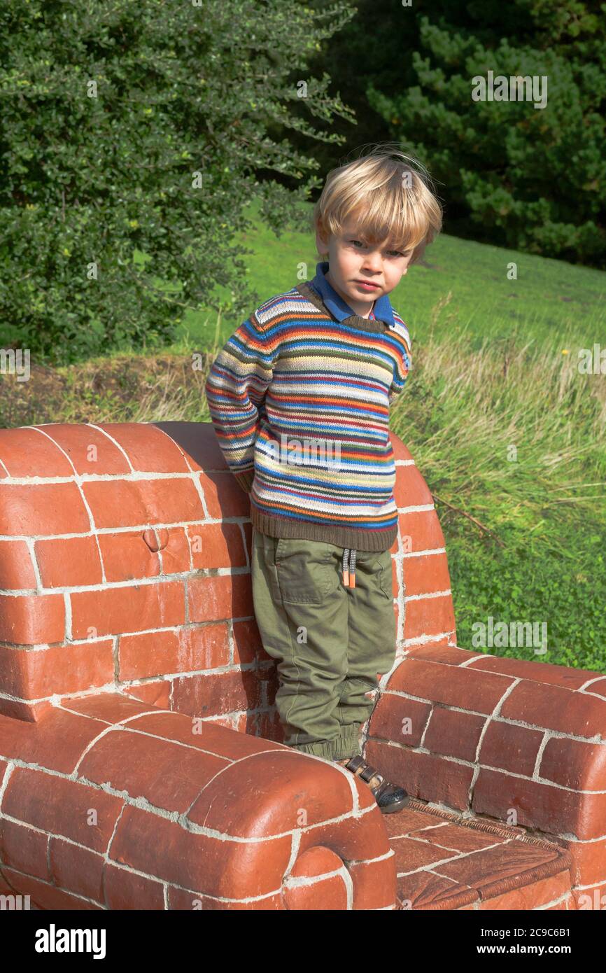 Little boy (2/3 anni) si trova su 'Se Bryck', una scultura di Amy Cooper, Tremenheere Scupture Gardens, Penzance, Cornwall, UK. MODELLO RILASCIATO Foto Stock