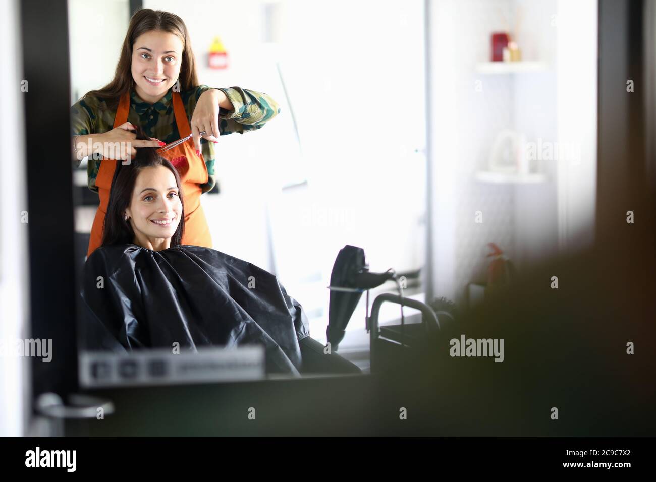 Parrucchiere e cliente guardare nello specchio e ridere Foto Stock