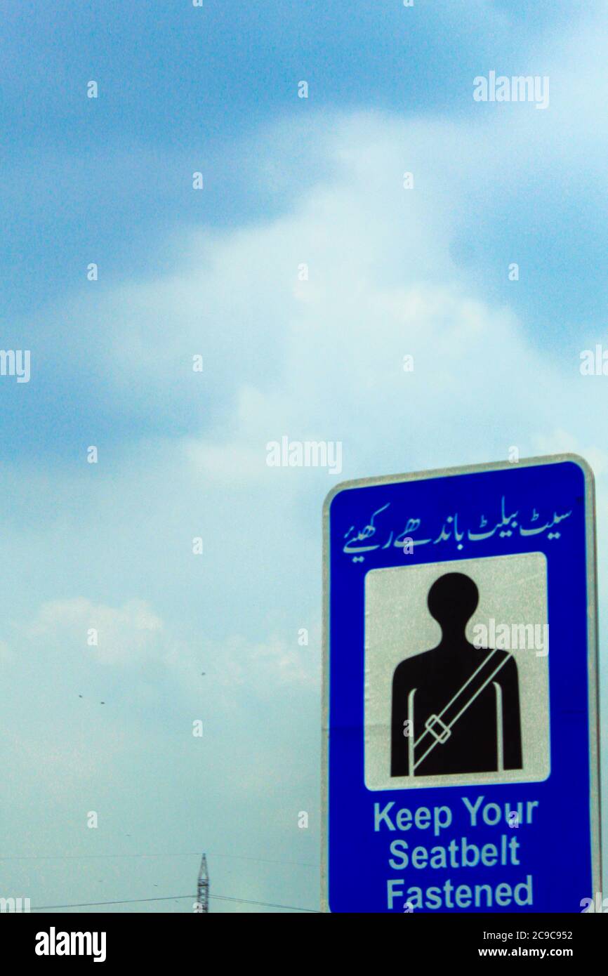 Allacciare la segnaletica stradale della cintura di sicurezza in urdu e in  inglese in Pakistan in autostrada Foto stock - Alamy