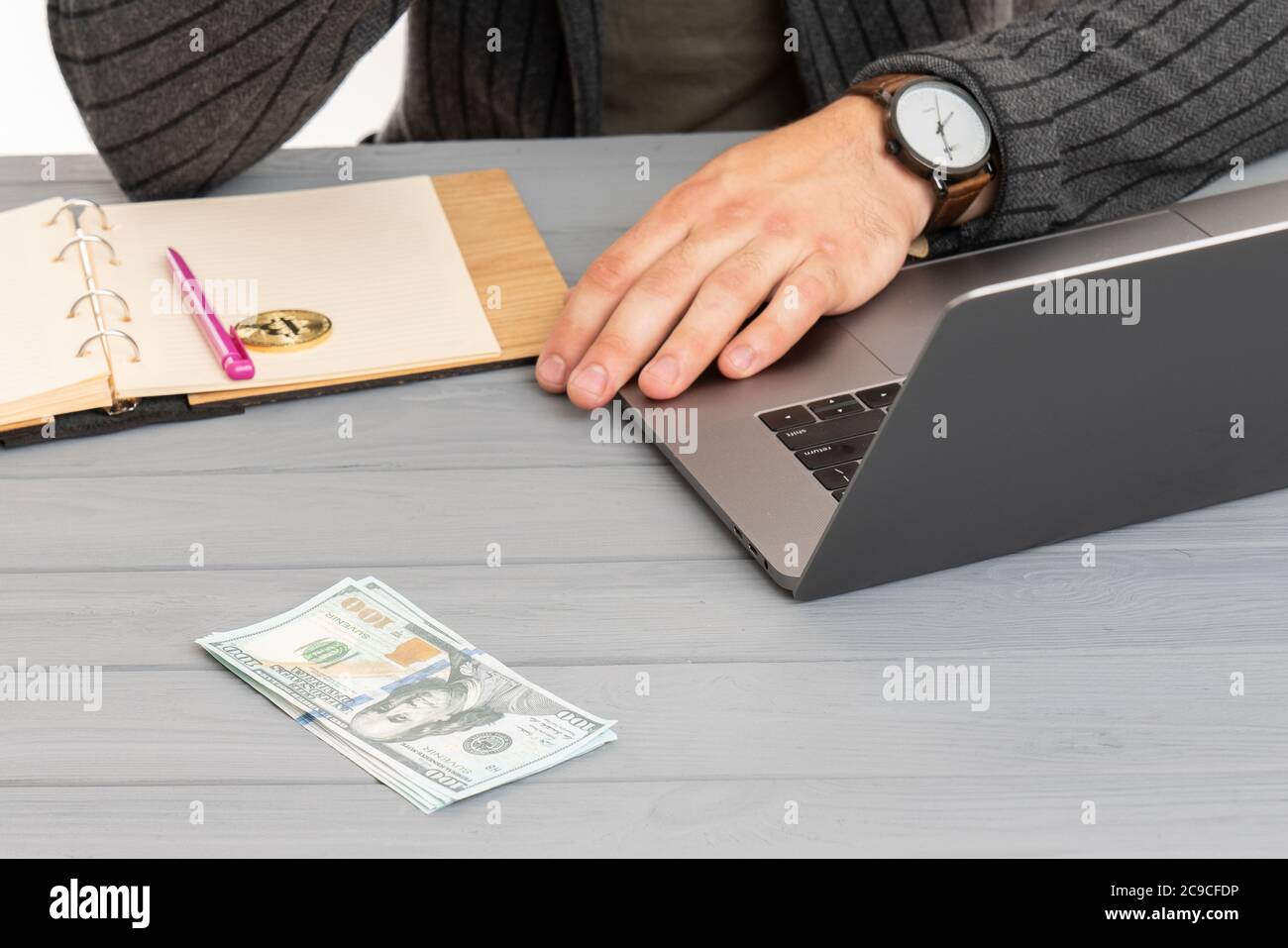 Primo piano mano uomo con orologio vicino Bitcoin, portatile e dollari di conto Foto Stock