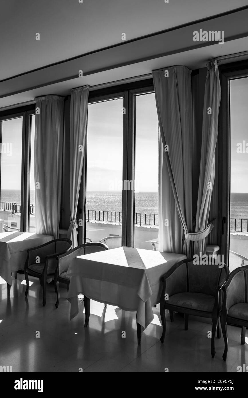 I tavoli di un hotel con una splendida vista sul mare dalla finestra. La luce entra attraverso la finestra in una giornata estiva. Vacanze, relax, lusso, Foto Stock
