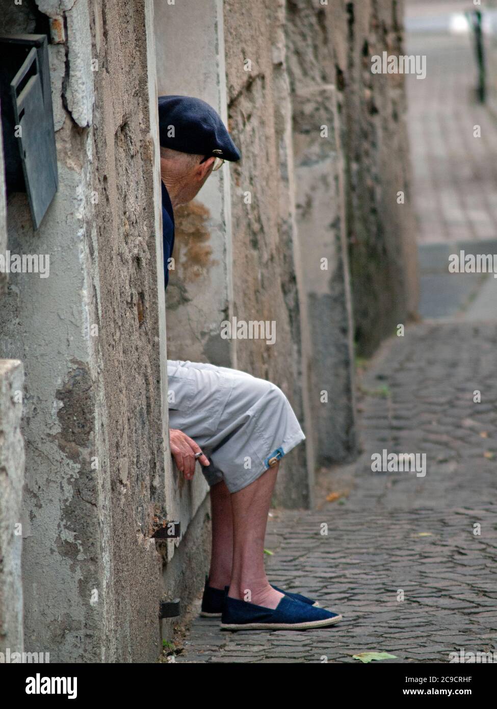Godendo una sigaretta su un gradino della porta nel villaggio Di Serignan Foto Stock