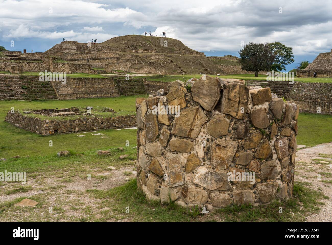 Una colonna rotonda in pietra di fronte alla piazza Sunken sulla piattaforma Nord delle rovine precolombiane Zapotec di Monte Alban a Oaxaca, Messico. UN UNESCO Foto Stock