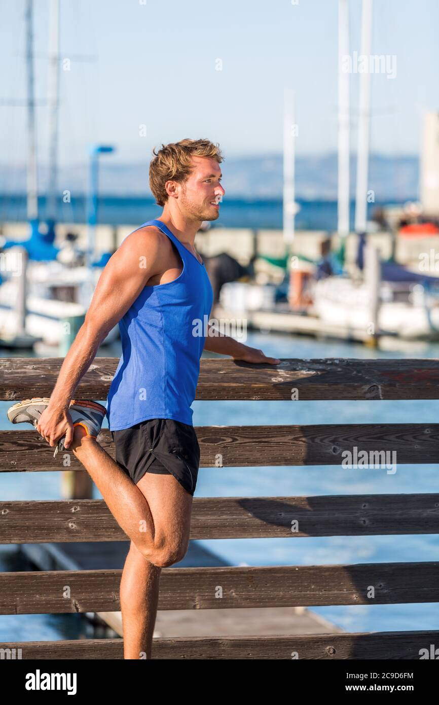 Atleta che allunga le gambe prima di correre nel porto di San Francisco Bay - stile di vita cittadino. Fitness Runner fare riscaldamento prima di allenamento cardio. Foto Stock
