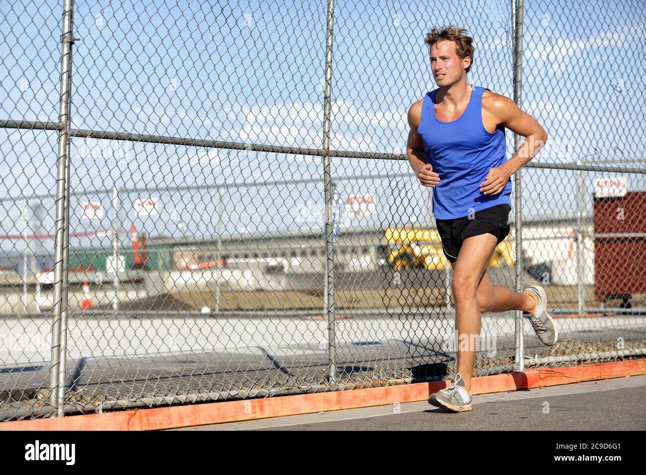 Runner man Running - stile di vita urbano. Giovani sport atleta maschile jogging in grunge recinzione sfondo all'aperto in estate activewear. Vita attiva. Foto Stock