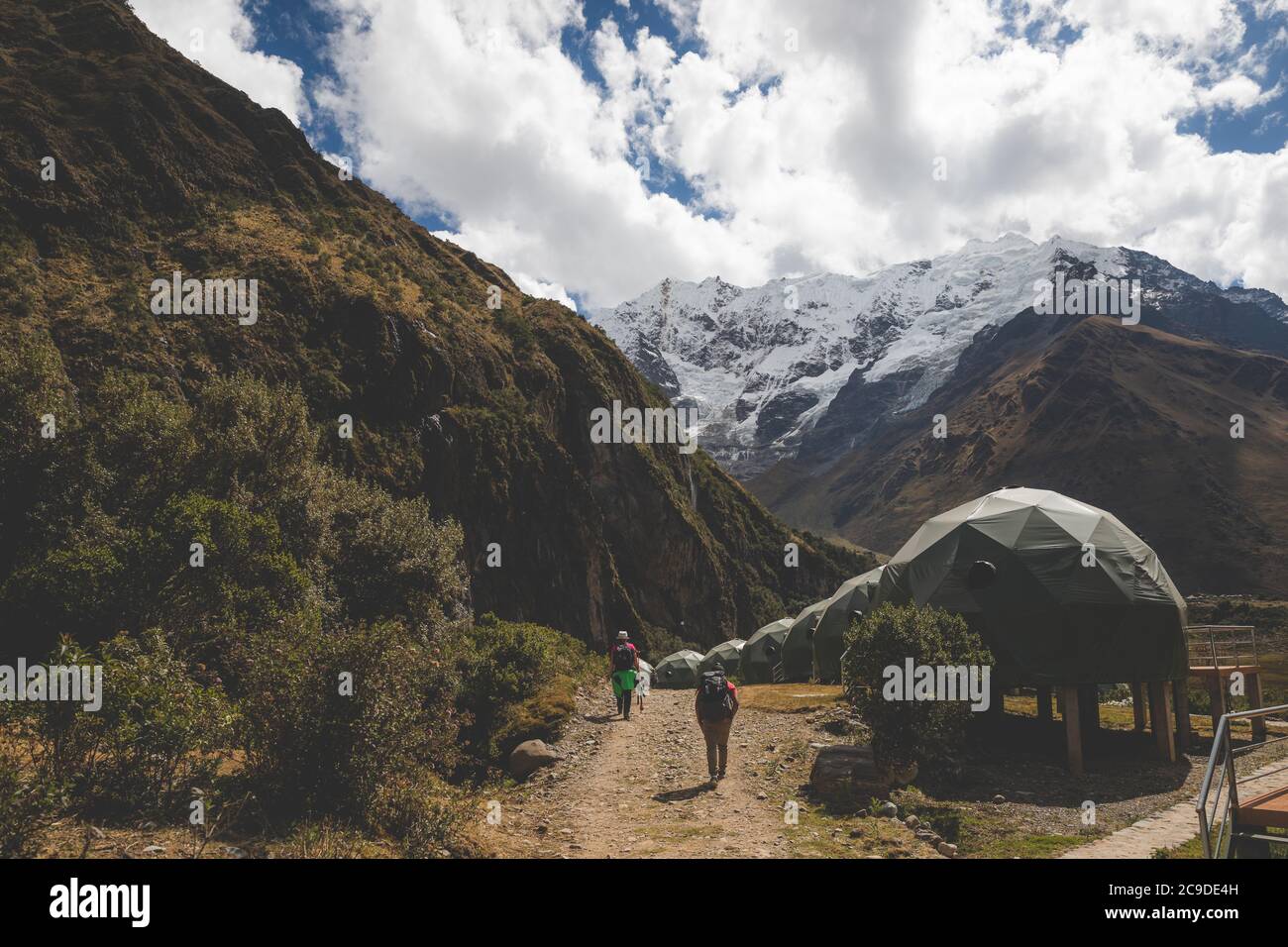 Due persone che camminano verso il monte Salkantay passando vicino al campeggio cupole dormienti Foto Stock