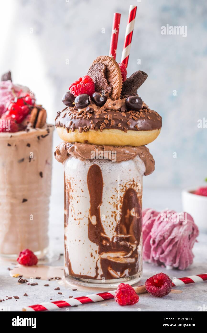 Frullato al cioccolato con frittella e ciambelle. Folle tendenza alimentare freakshake. Spazio di copia Foto Stock