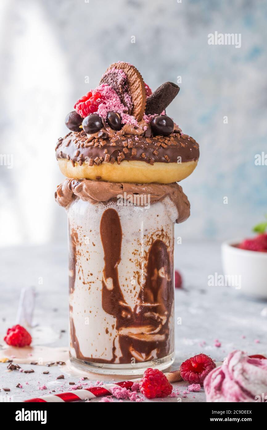 Frullato al cioccolato con frittella e ciambelle. Folle tendenza alimentare freakshake. Spazio di copia Foto Stock
