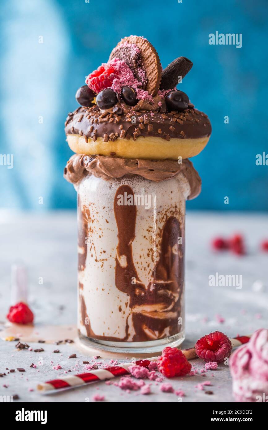Frullato al cioccolato con frittella e ciambelle. Folle tendenza alimentare freakshake. Spazio di copia Foto Stock