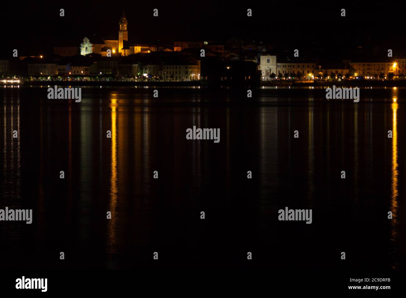 Vista della città di Arona di notte con luci che si riflettono sul lago Foto Stock