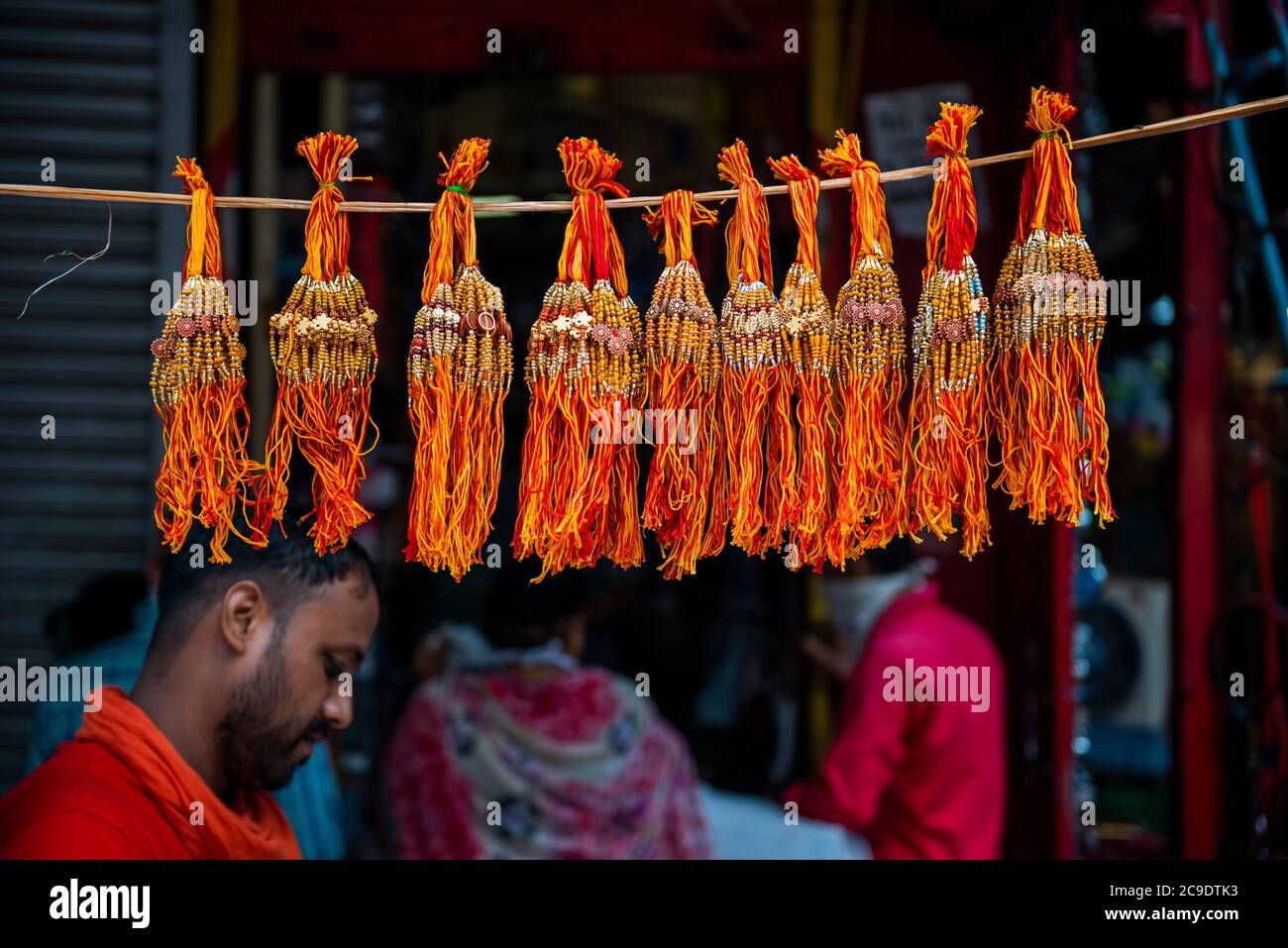 Mazzi di rakhis in vendita sono appesi su una corda di fronte a un shop.Rakhshabandhan è festa di fratello relazione sorella. In questo giorno sorelle di tutte le età legano un talismano o amuleto popolarmente noto come Rakhi, intorno al polso dei loro fratelli, proteggendoli simbolicamente dal male, in cambio ricevono doni dai loro fratelli come segno di amore e di abbondanza di benedizioni. Tradizionalmente i fratelli a loro volta si assumono le responsabilità di stare con le loro sorelle in tempi difficili per proteggerli e curarli. Foto Stock