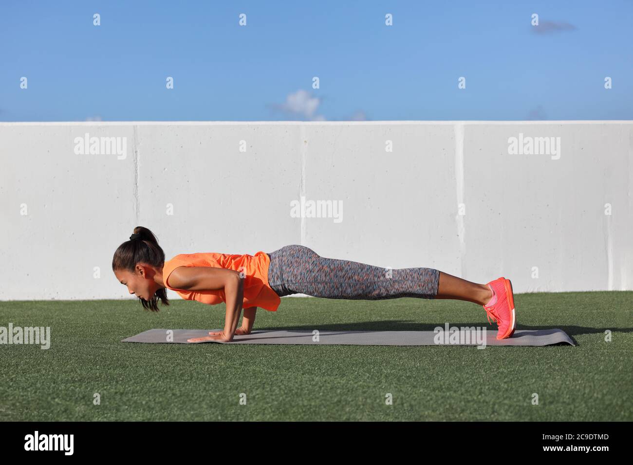 Yoga fitness donna pratica chaturanga posa spingere su o premere su tappetino di esercizio a casa all'aperto. Giovane ragazza in forma e sana che fa il corpo del nucleo del mattino Foto Stock