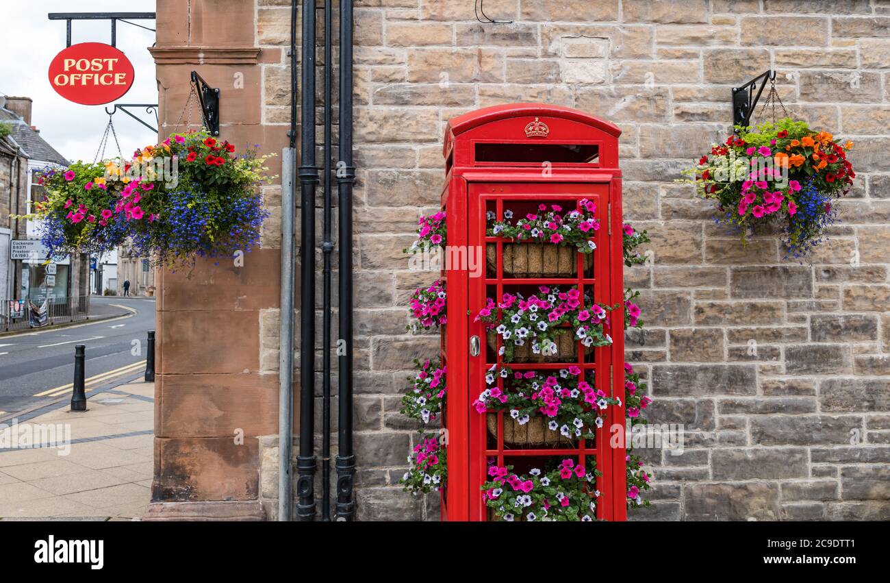 Iconico telefono rosso britannico convertito in cestini di fiori e segno dell'Ufficio postale, Tranent, East Lothian, Scozia, Regno Unito Foto Stock