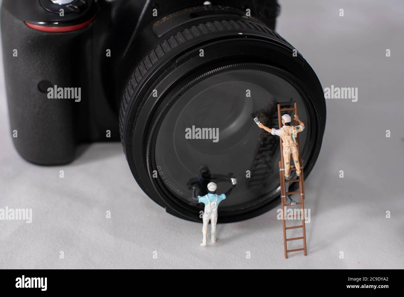 Le lavavetri in miniatura puliscono l'obiettivo di una fotocamera digitale. Foto Stock