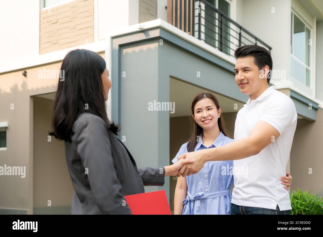 Felice coppia asiatica alla ricerca della loro nuova casa e agitare le mani con broker immobiliare dopo un accordo. Giovane coppia handshaking agente immobiliare dopo Foto Stock