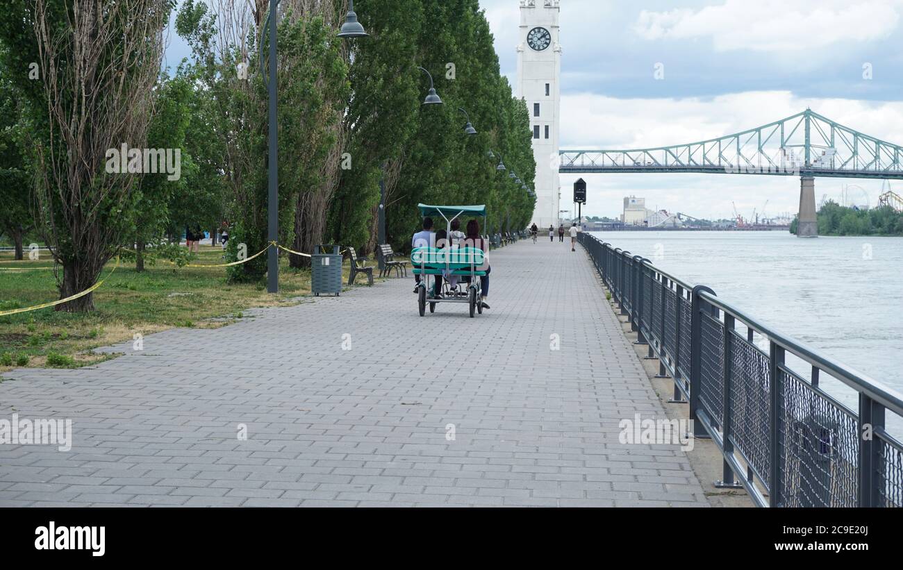 Montreal, QC/ Canada - 25/06/2020: Una famiglia fa un giro in quadriciclo nel vecchio porto dopo la facilità del blocco del coronavirus. Lo sfondo è l'orologio Foto Stock