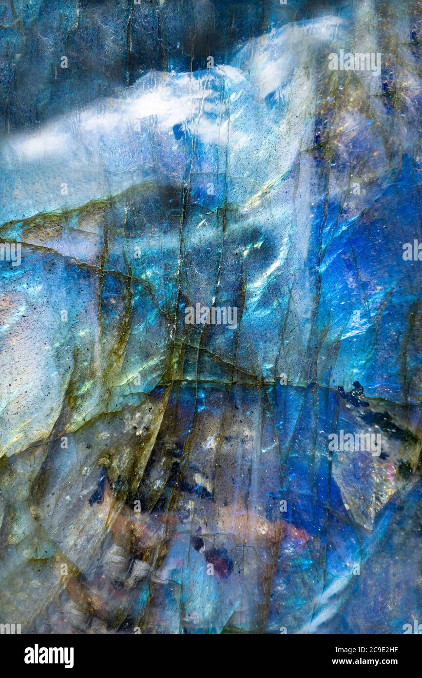 Macro foto di una colorata pietra blu labradorite con un surreale paesaggio montano. L'illuminazione mette in luce la consistenza minerale iridescente. Foto Stock