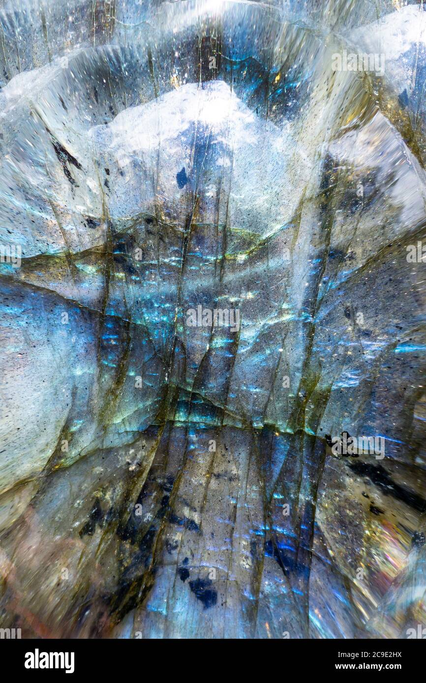 Macro foto di una colorata pietra blu labradorite con un surreale paesaggio montano. L'illuminazione mette in luce la consistenza minerale iridescente. Foto Stock