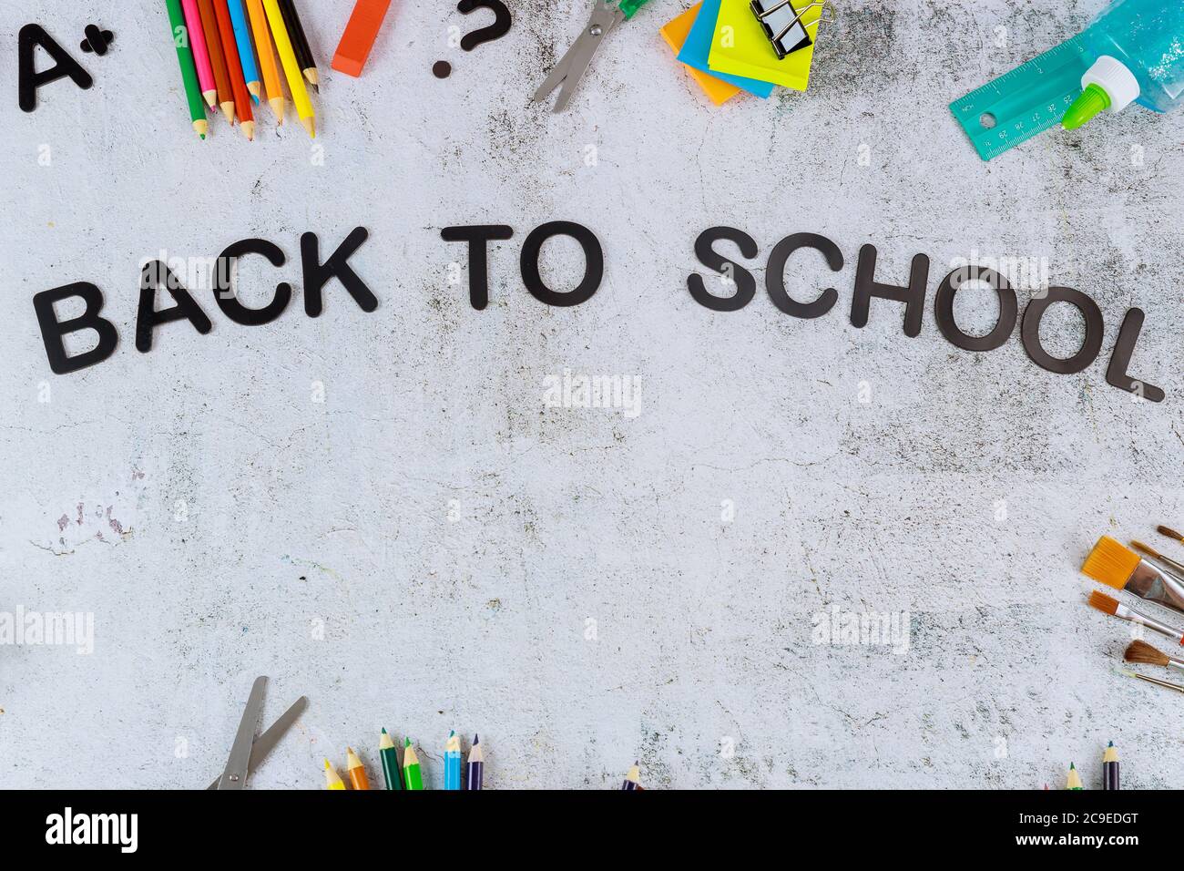 Sfondo delle forniture scolastiche con testo di ritorno a scuola. Vista dall'alto. Foto Stock