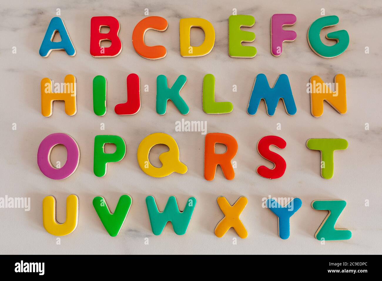 Lettere colorate su sfondo in marmo, ordine alfabetico, vista dall'alto Foto Stock