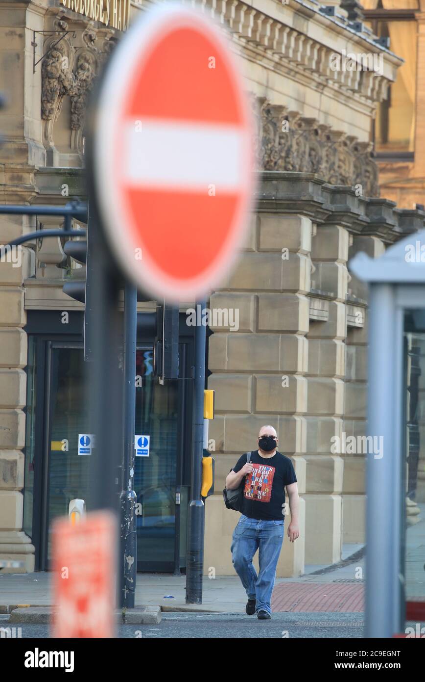 Un uomo che indossa una maschera facciale cammina attraverso il centro di Bradford, West Yorkshire, una delle aree in cui sono state attuate nuove misure per prevenire la diffusione del coronavirus. Sono state introdotte norme più severe per le persone nella Greater Manchester, in alcune zone del Lancashire orientale e nello Yorkshire occidentale, che vietano ai membri di famiglie diverse di incontrarsi in luoghi chiusi. Foto Stock