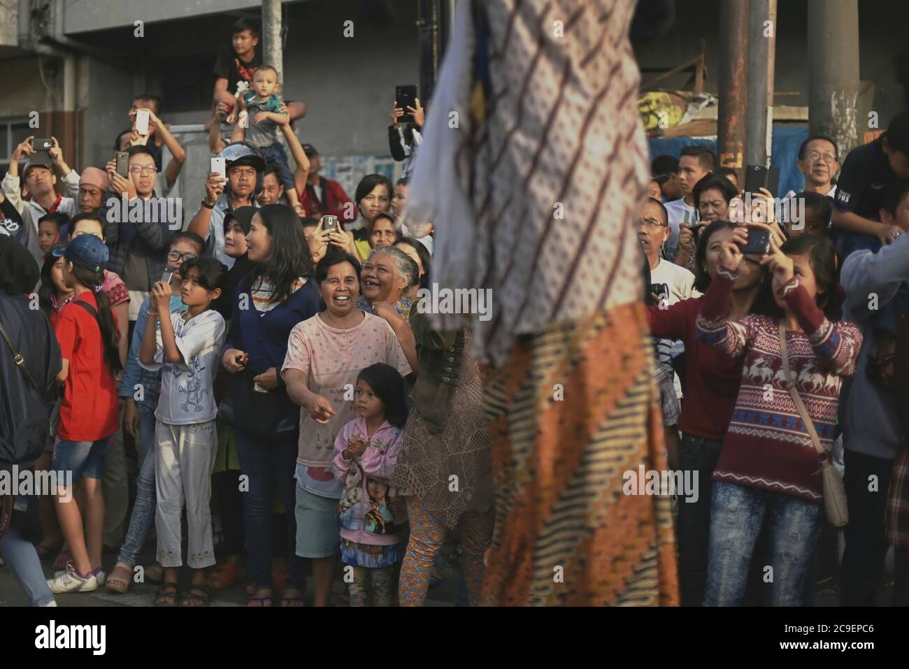Gli spettatori si rallegrano e scattano foto di camminatori con palafitte che indossano costumi di carattere wayang durante la sfilata culturale del Bandung Lantern Festival 2015. Foto Stock