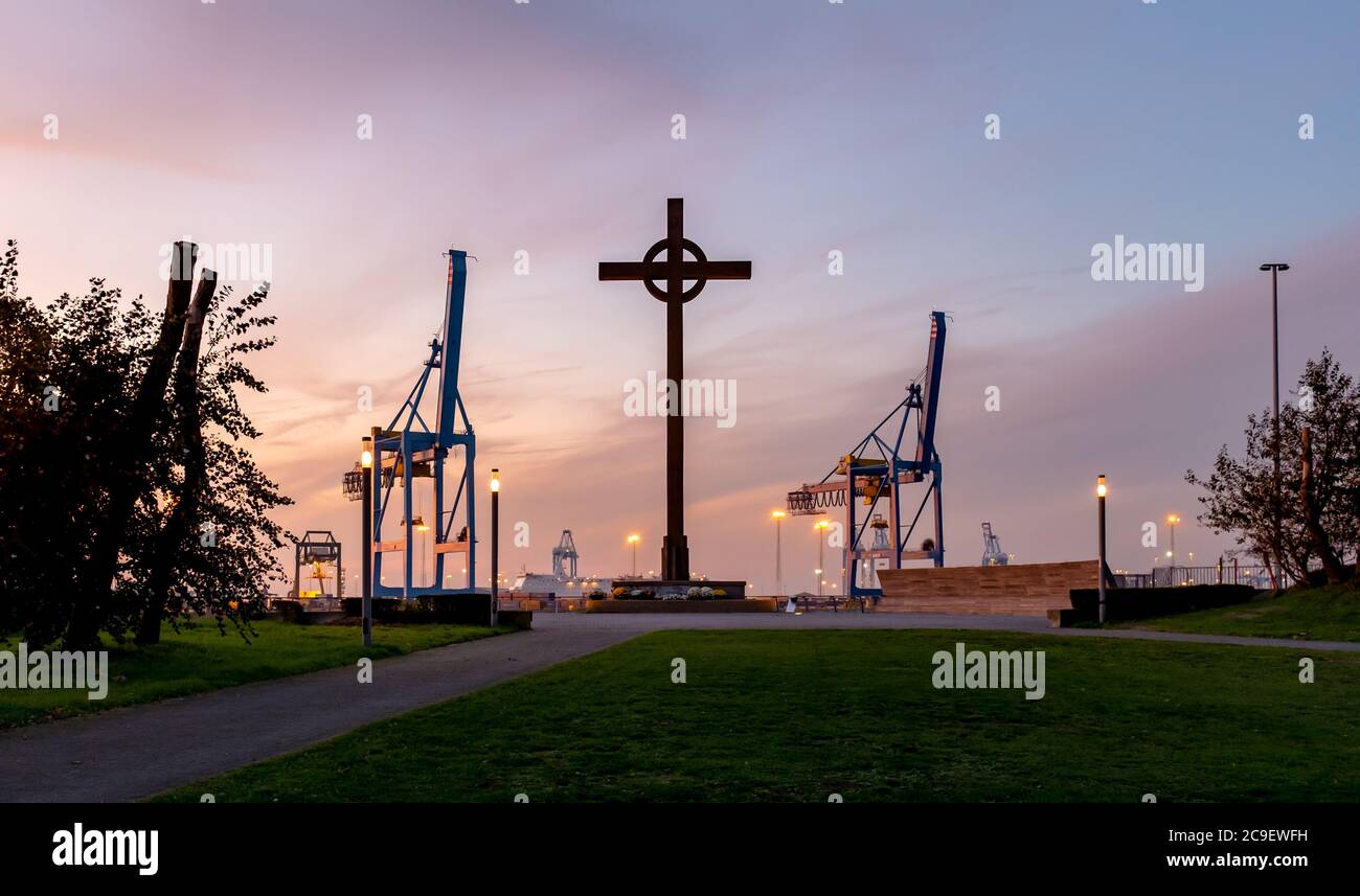 Vista silhouette del monumento chiamato Visserkruis e gru portuali nel porto internazionale di Zeebrugge Foto Stock