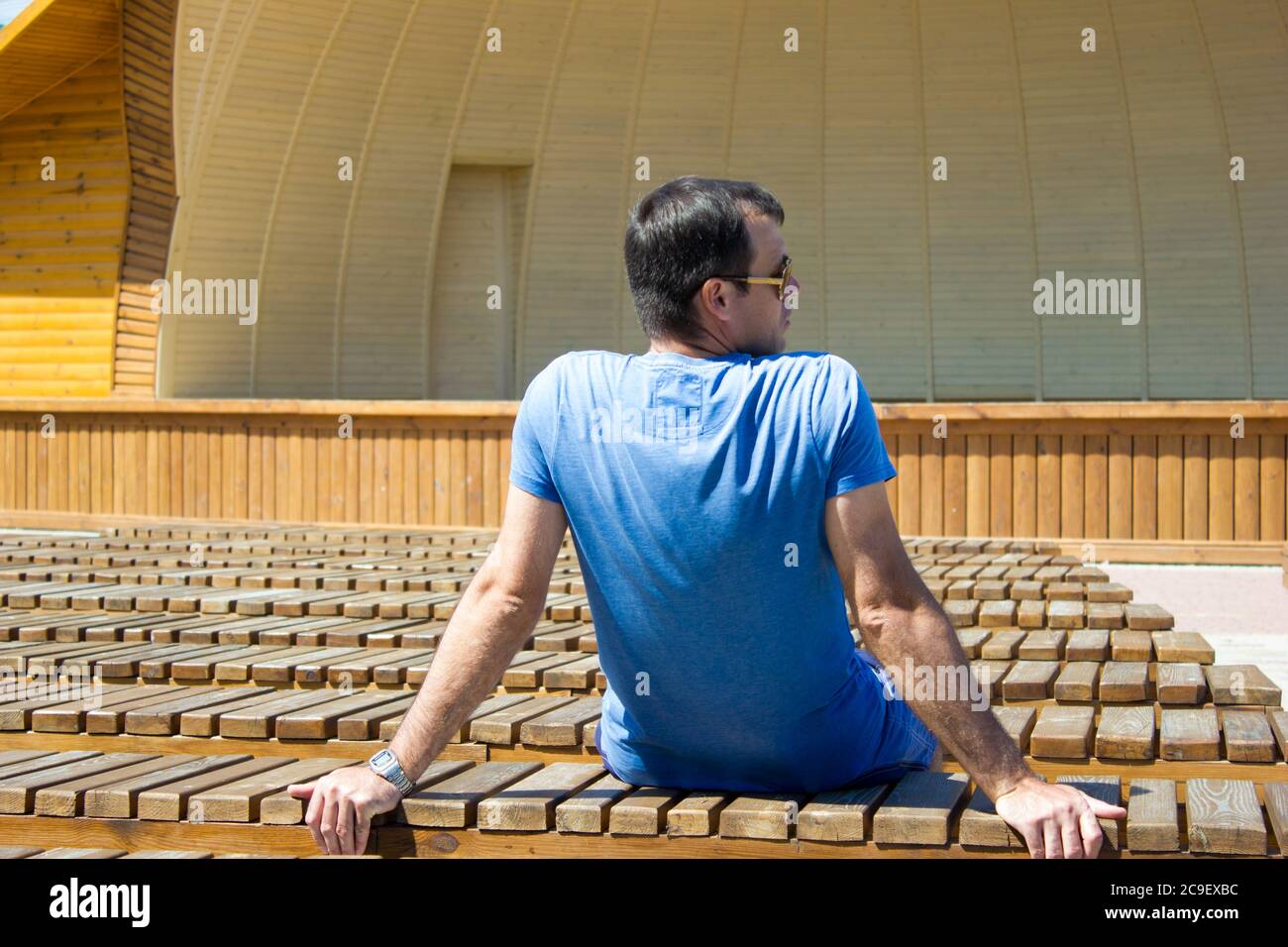 L'uomo è seduto da solo nella schiena tra le tante panchine del teatro di strada Foto Stock