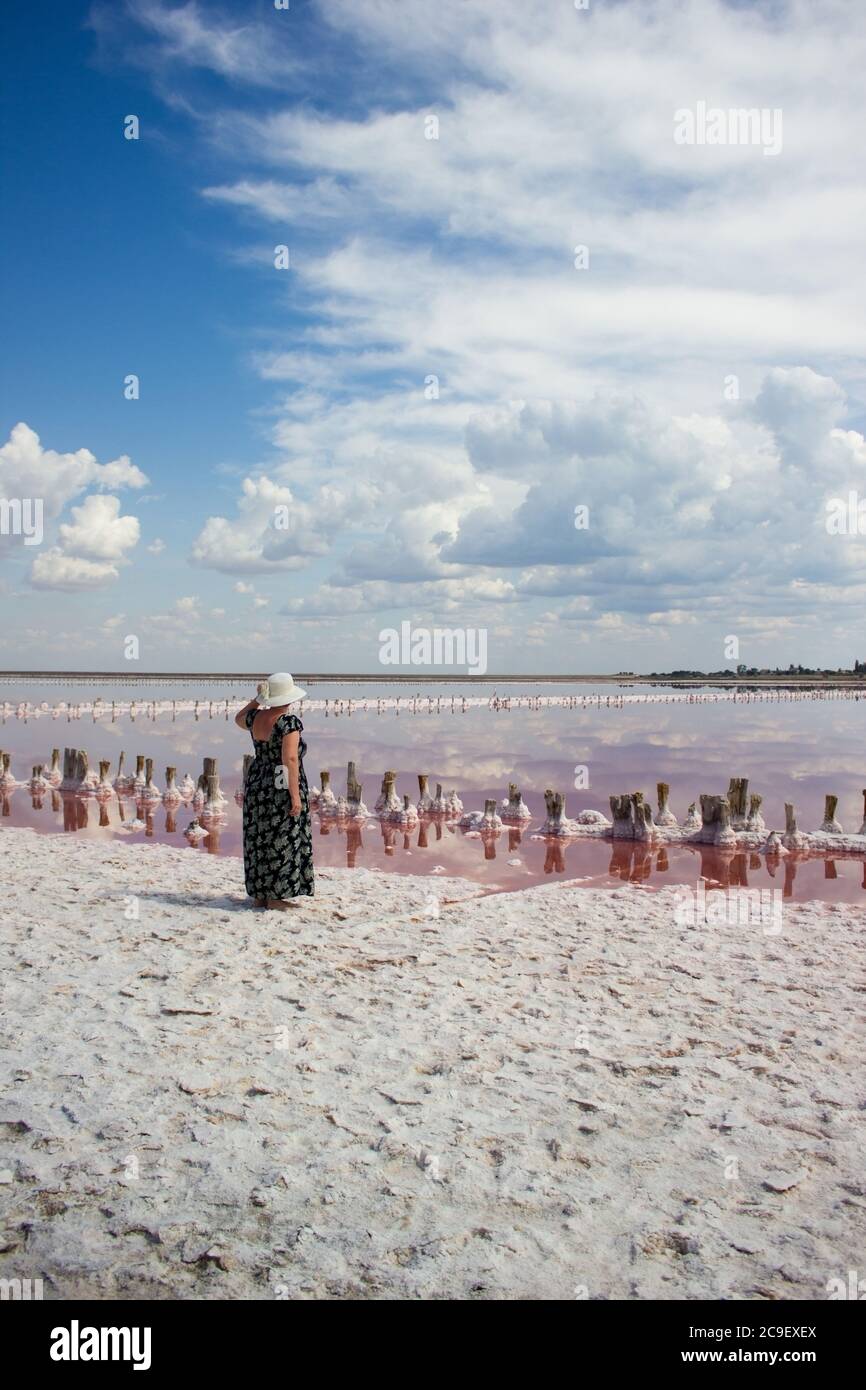 Donna in un cappello su un paesaggio di nuvole acqua e orizzonte - sullo sfondo di una pianta di produzione di sale Foto Stock