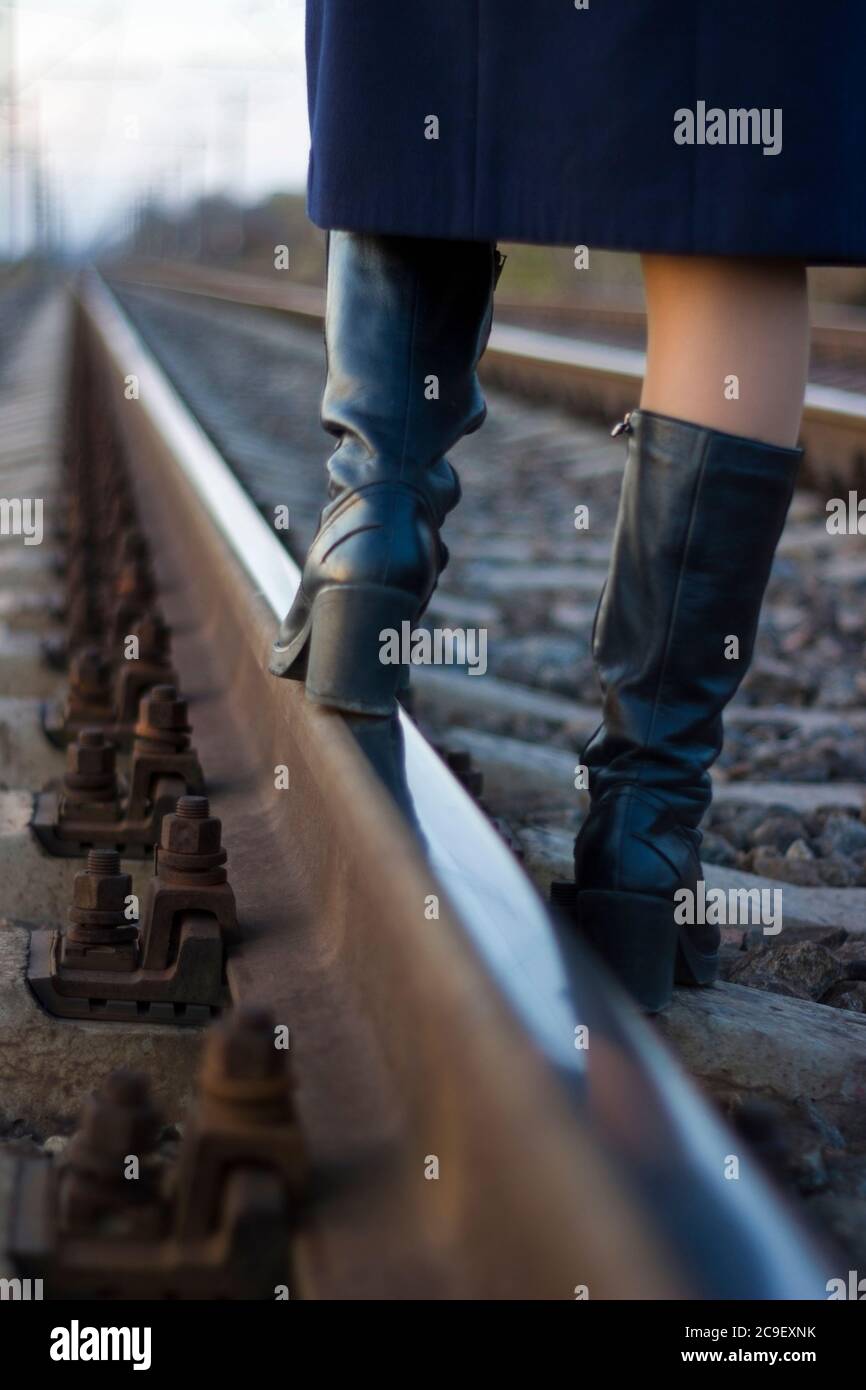 Ragazza cammina su rotaie ferroviarie in un cappotto e stivali - viaggio,  depressione, stile di vita Foto stock - Alamy