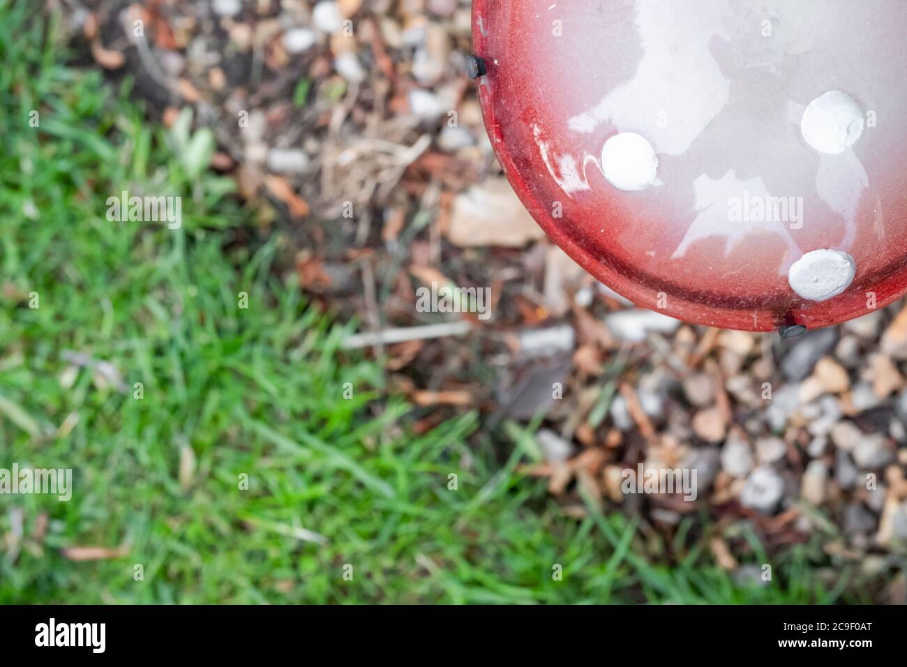 Fuoco superficiale di un fungo di vetro ornato fatto in casa visto installato in una ghiaia, adiacente ad una zona labile. Foto Stock