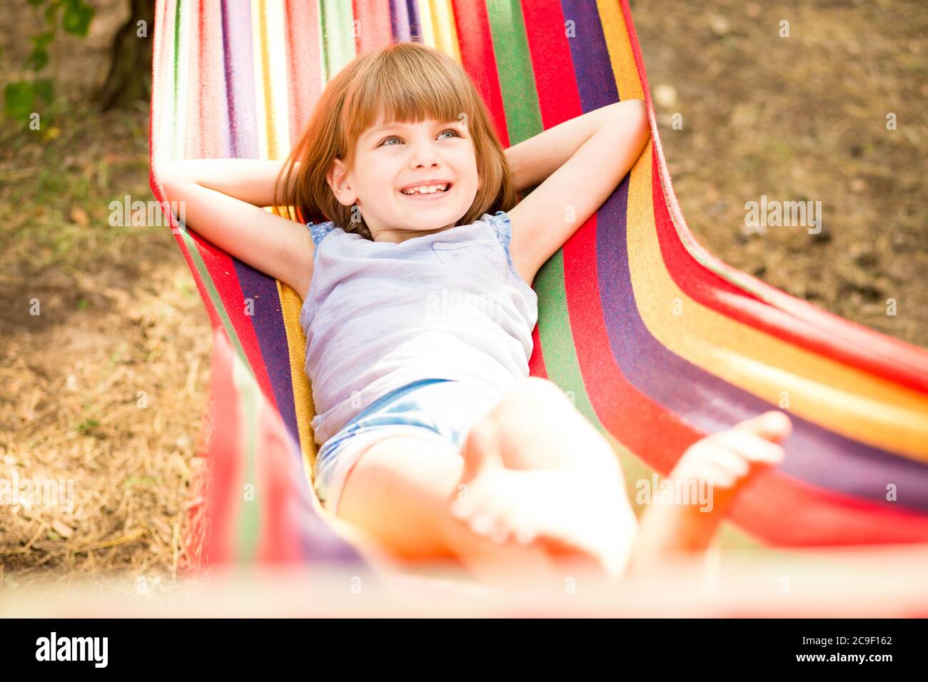 Felice bella bambina che si rilassa in amaca colorata nella foresta estiva. Vacanze estive Foto Stock