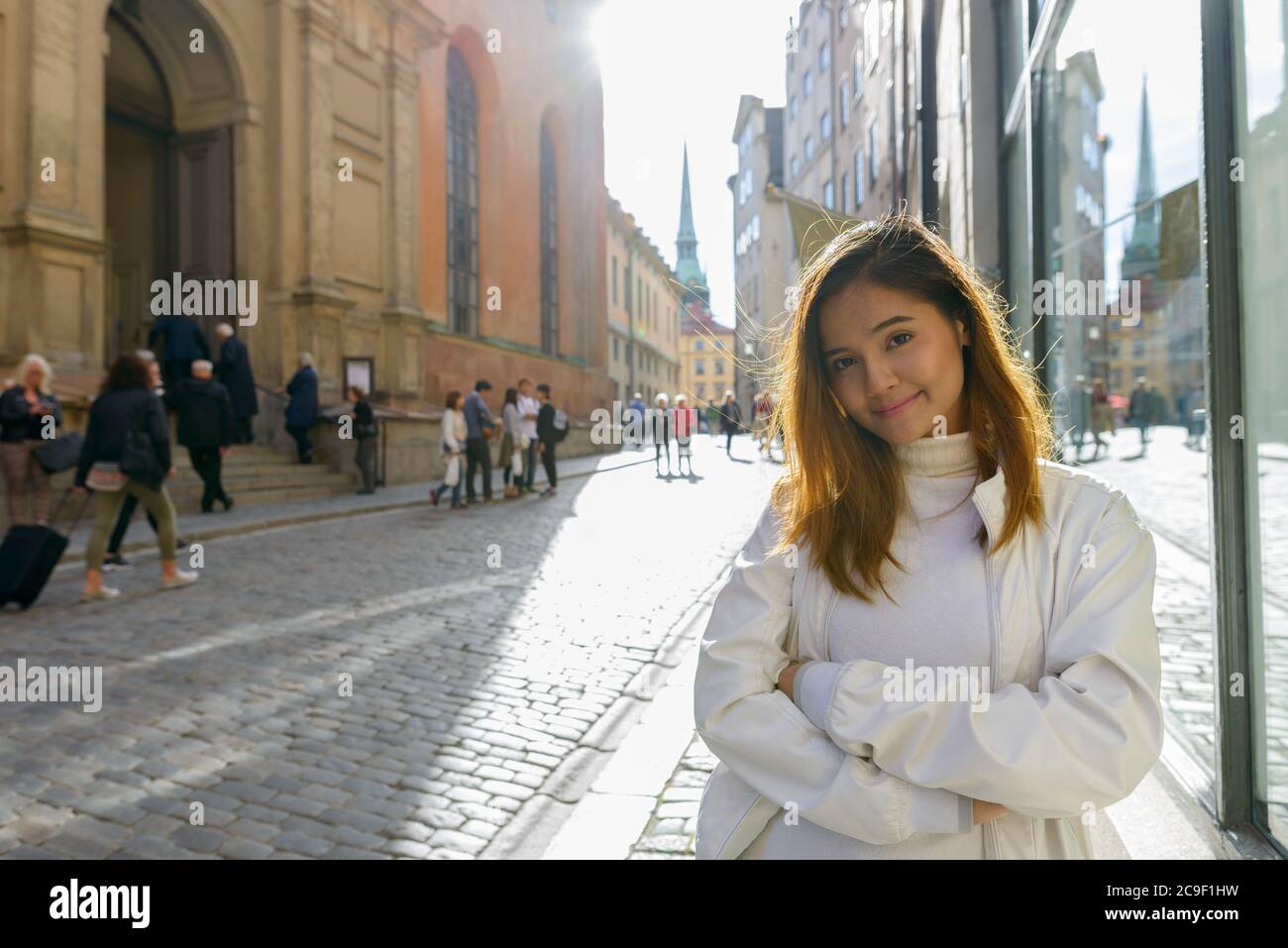 Felice giovane bella donna turistica asiatica sorridente con le braccia incrociate per le strade della Svezia Foto Stock