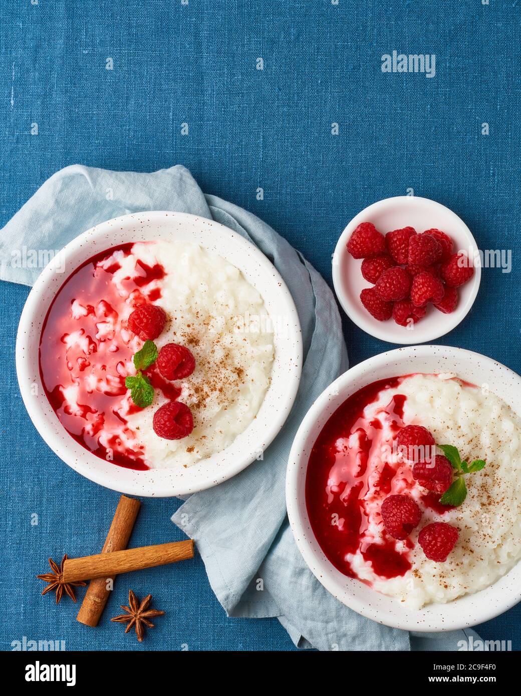 Budino di riso. Dessert al latte francese con lamponi. Tessuto blu. Vista dall'alto, verticale, spazio di copia Foto Stock