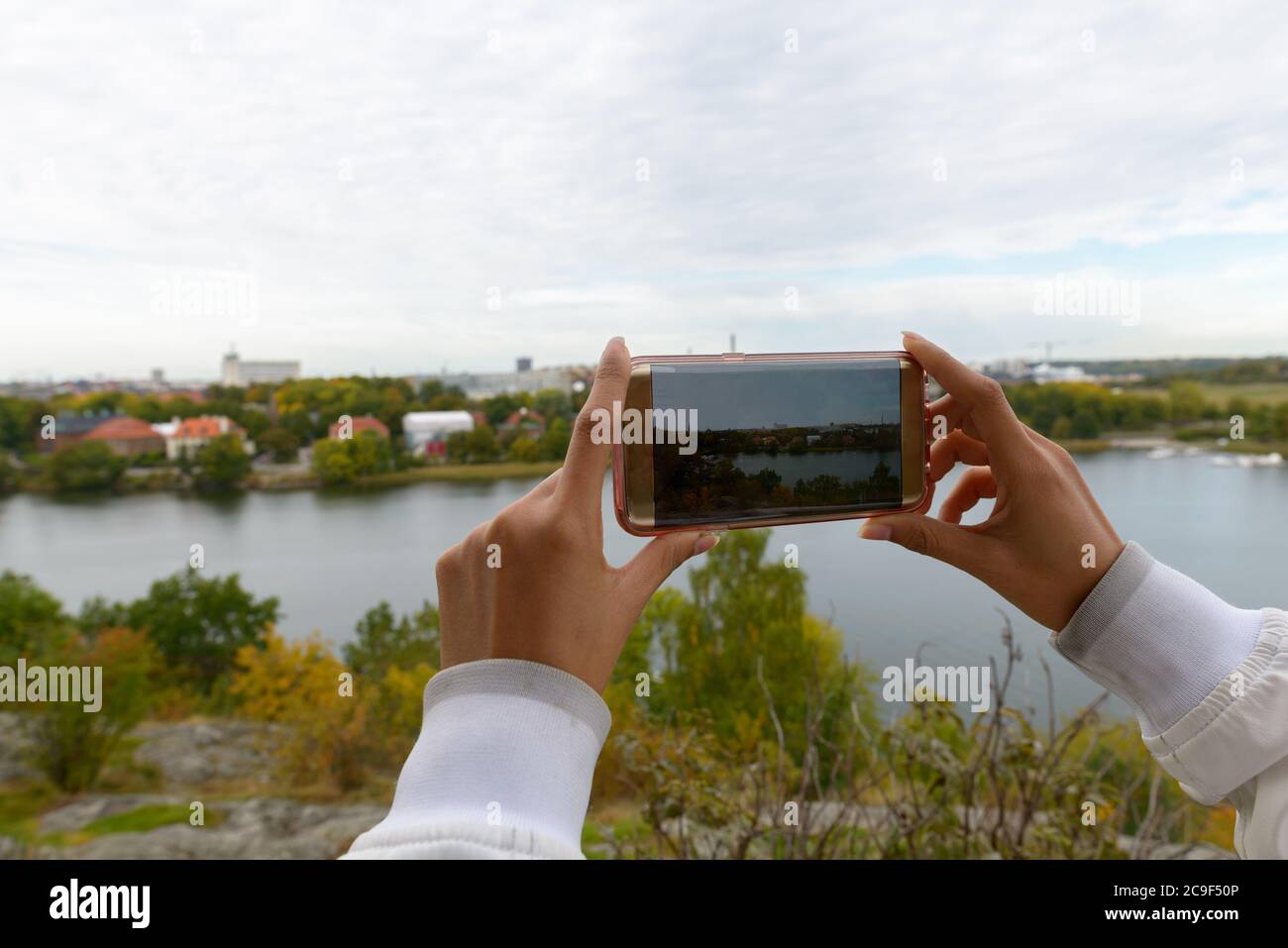 Mano di turista donna scattare foto con telefono del parco e lago in Svezia Foto Stock