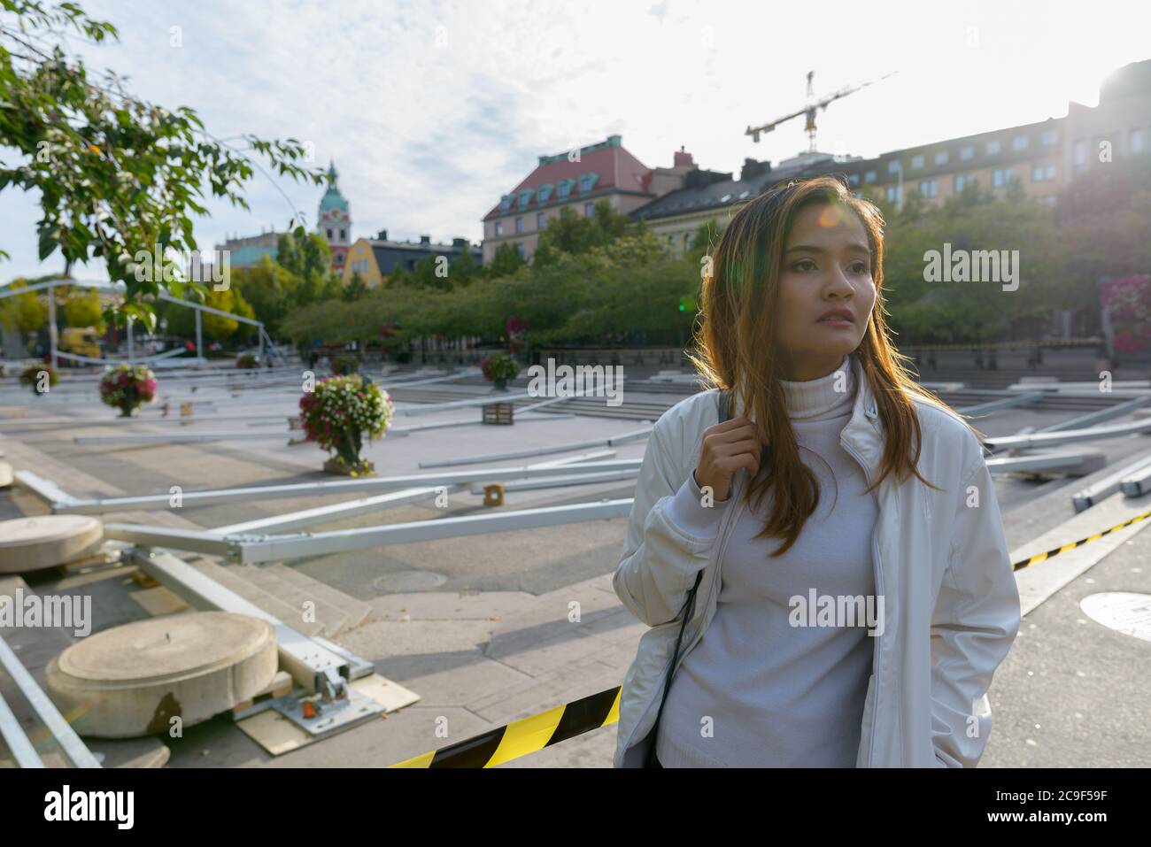 Giovane bella donna turistica asiatica pensando in piazza vuota città all'aperto Foto Stock