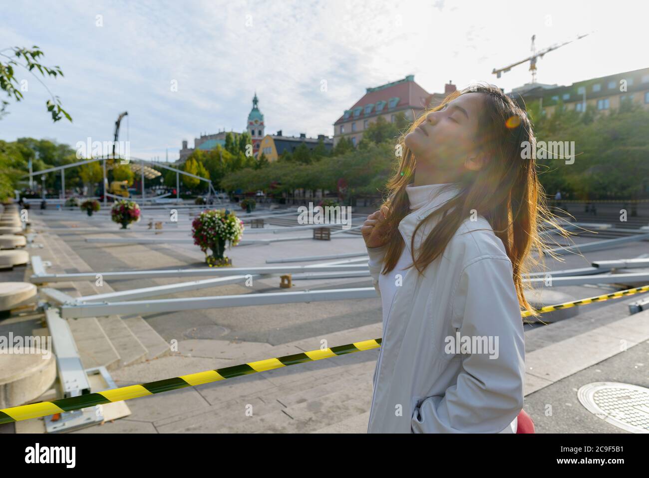 Giovane bella donna turistica asiatica con gli occhi chiusi nella piazza vuota della città all'aperto Foto Stock