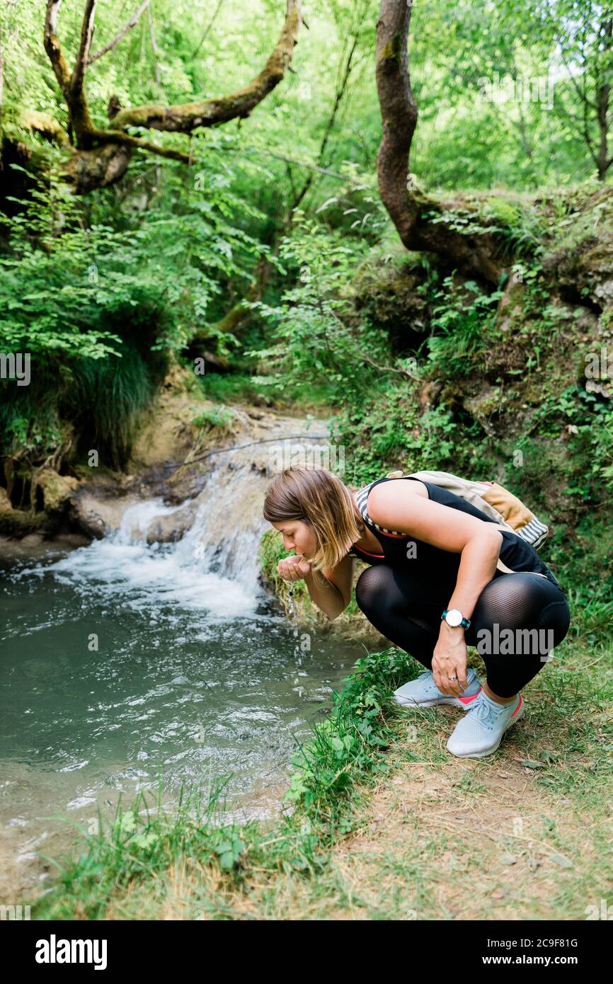 Giovane donna natura esploratore acqua potabile dalla primavera Foto Stock