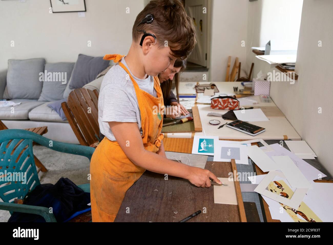 Ragazzo con impianto cocleare imparare a fare linocut piatto lino mentre la stampa in uno studio di arte in Carmarthenshire Galles UK KATHY DEWITT Foto Stock