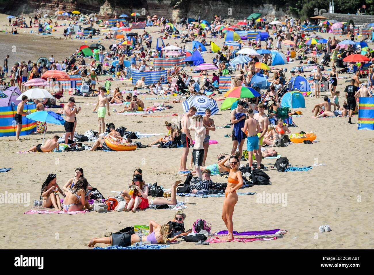 La gente sulla spiaggia di Barry Island, come primo ministro per il Galles, Mark Drakeford, ha annunciato che da lunedì fino a 30 persone possono incontrarsi all'esterno mantenendo le distanze sociali nell'ultimo allentamento delle misure di coronavirus in Galles. Foto Stock